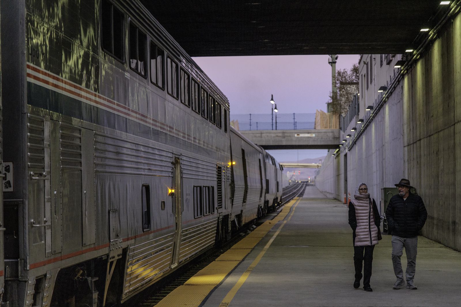 And older couple walks along the platform as the sun sets in Reno.